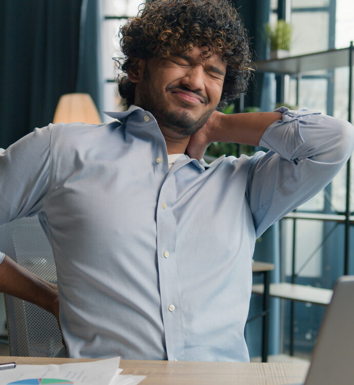 Man in office stretching neck and back, relieves discomfort, ergonomic break.