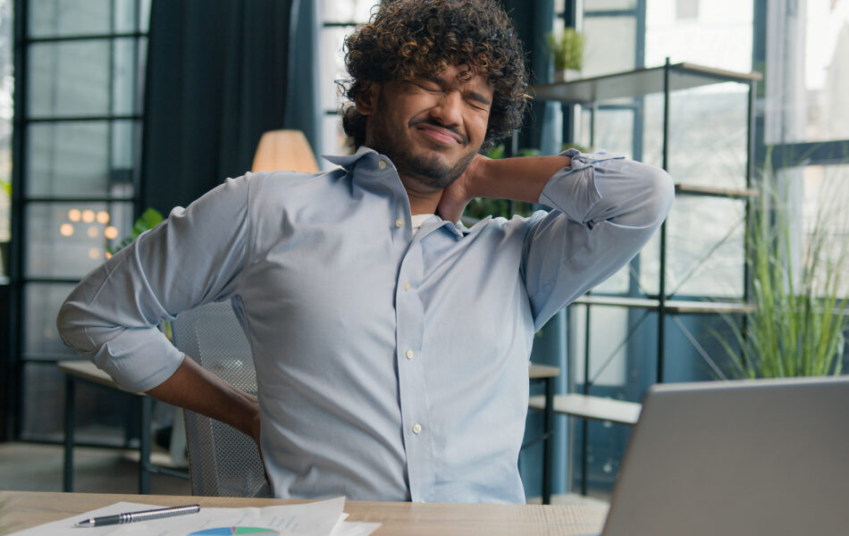 Man in office stretching neck and back, relieves discomfort, ergonomic break.